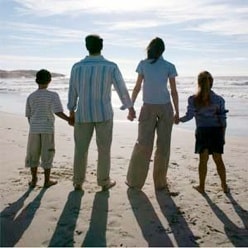 Family of four holding hands on the beach